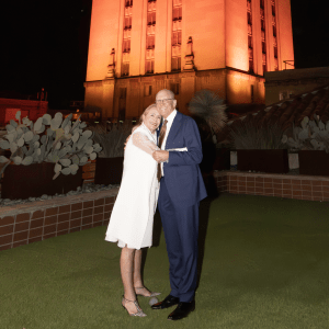 A man and woman hug at the base of the UT Tower.